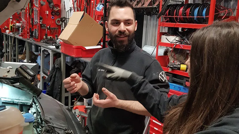 Några personer som arbetar med en bil i en bilverkstad.